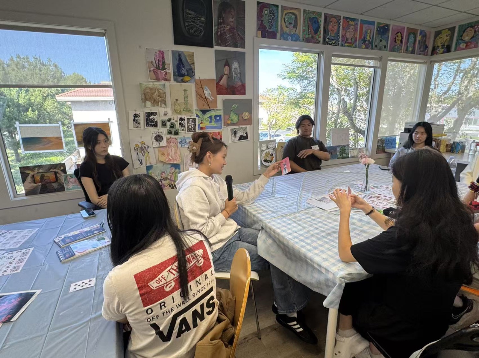 A studio table surrounded by participants and finished artworks